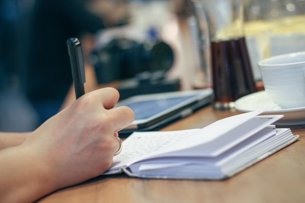 Person taking notes working on laptop