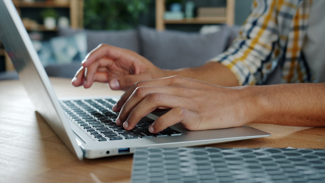 Person typing on laptop keyboard in workspace