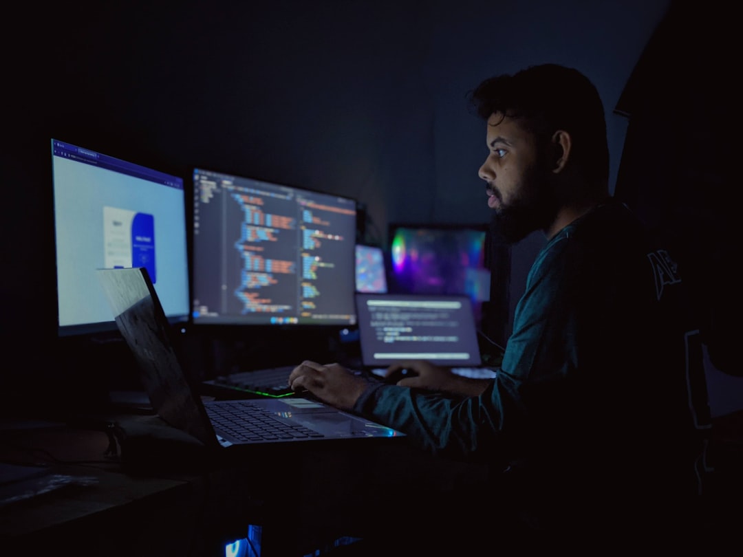 Programmer coding at workspace with multiple monitors