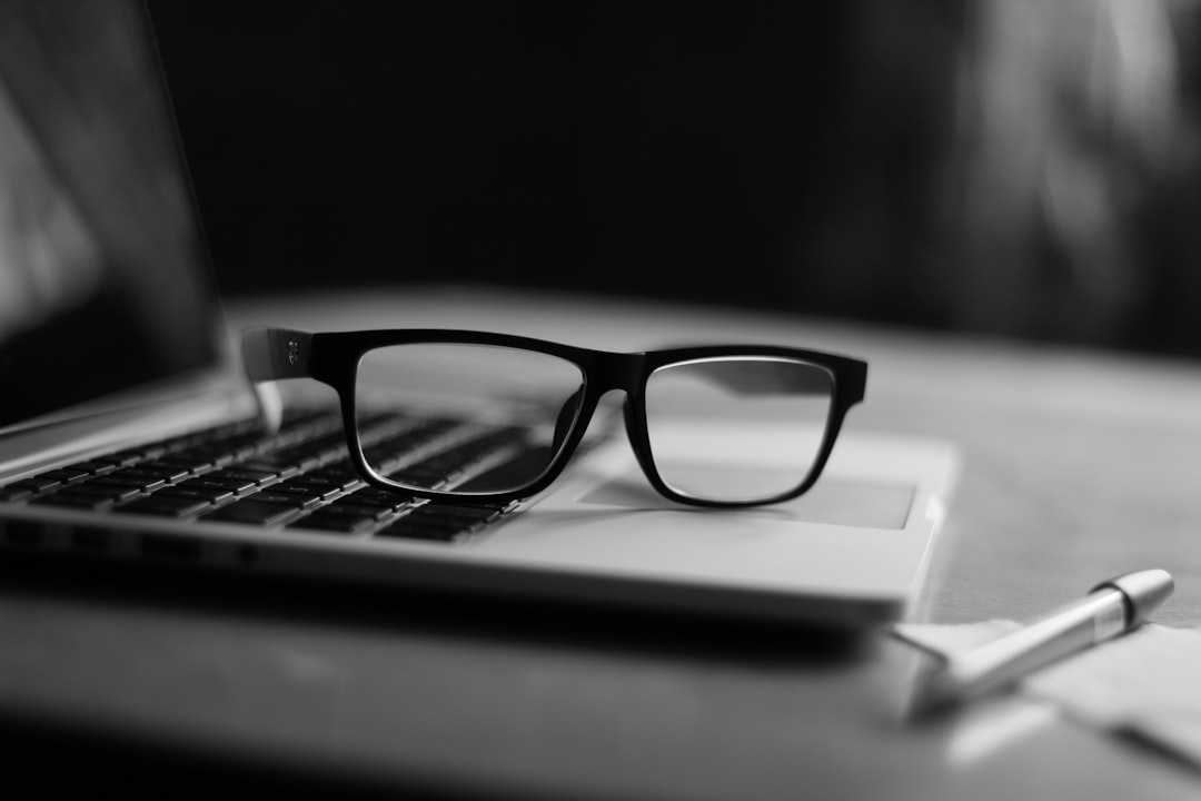 Eyeglasses resting beside a laptop