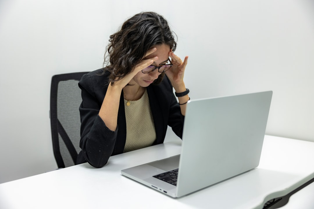 Person rubbing tired eyes at an office desk
