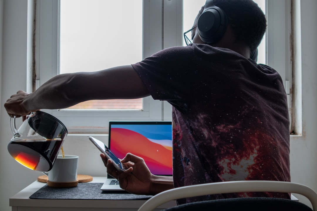 Person drinking coffee while working on laptop at home