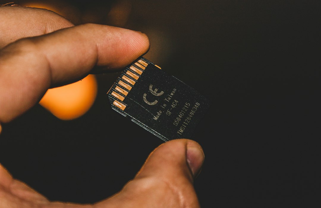 A micro SD card held between fingers showing gold contacts