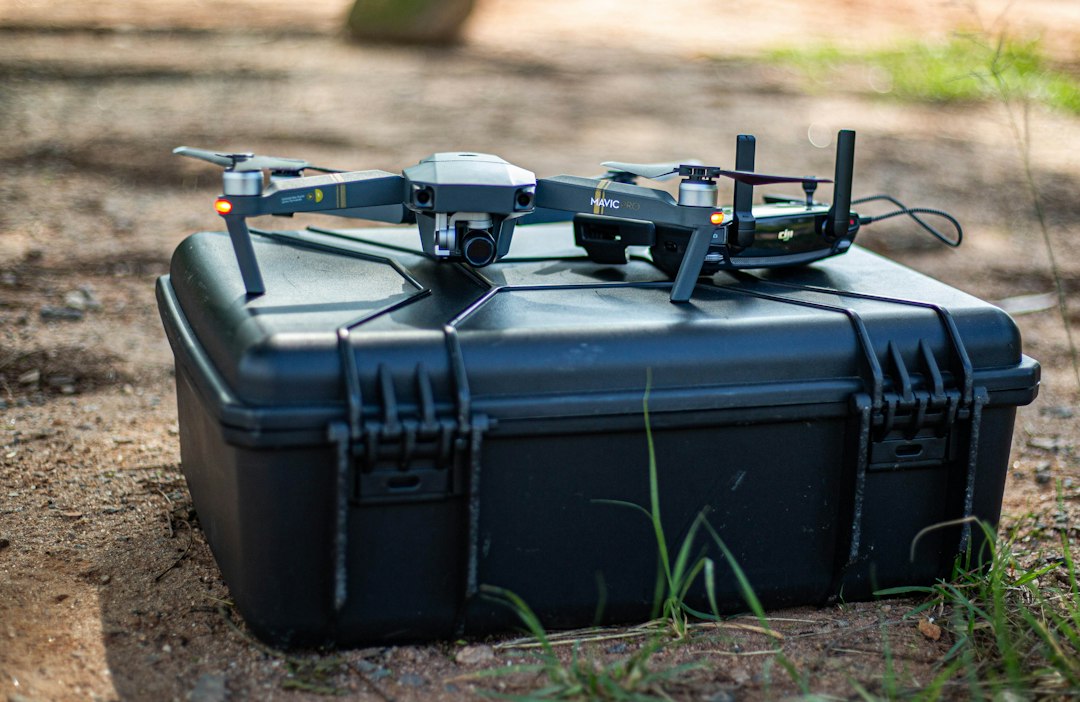 Two drones resting on a black protective carrying case outdoors