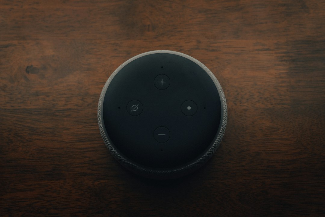 A smart speaker sitting on a wooden surface