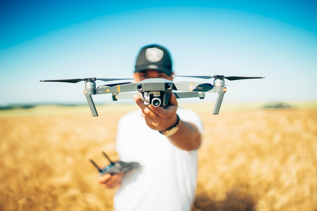 Person holding a small drone with its controller visible outdoors