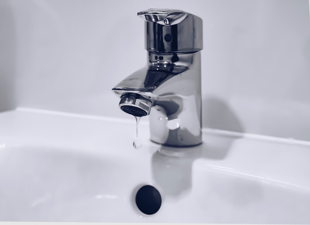 Faucet dripping into a white bathroom sink
