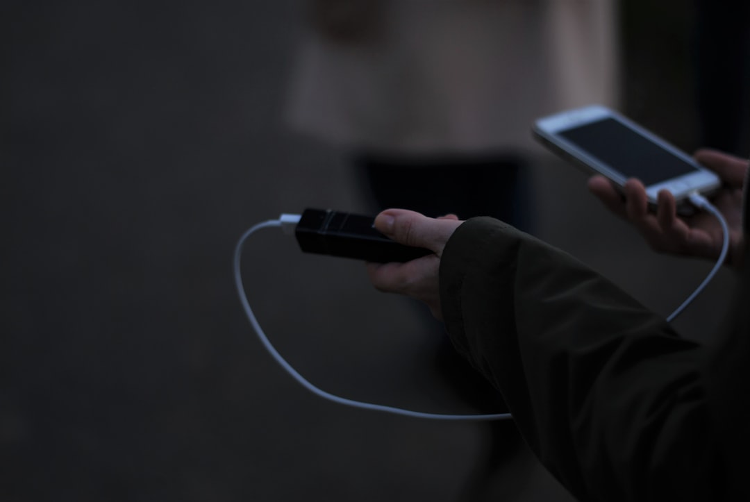 Hands holding a power bank charging a smartphone