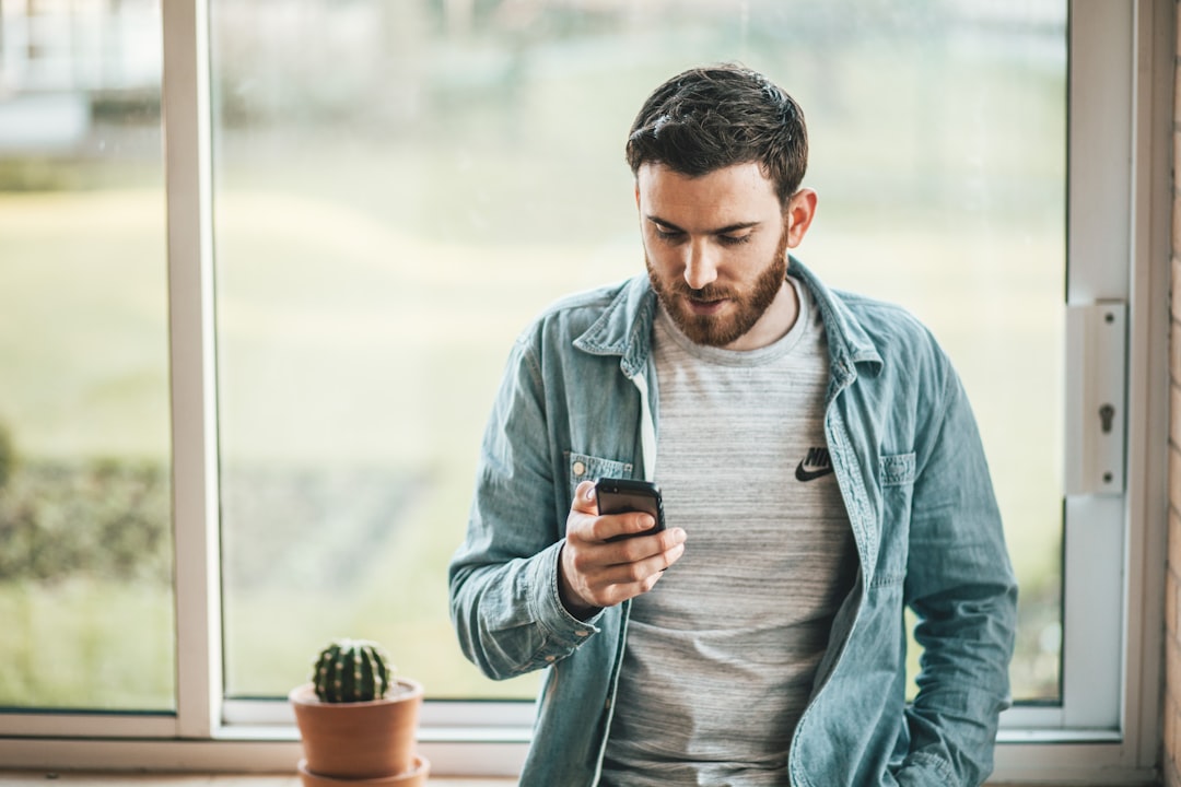 Man checking his phone by a window