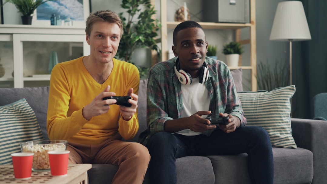Two friends playing video games together on a couch with controllers