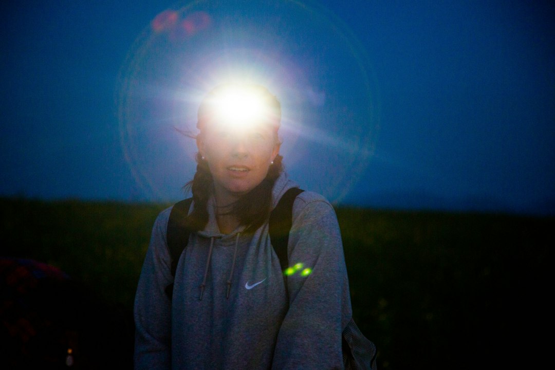 Person wearing a bright headlamp at dusk