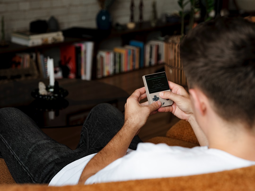 Man relaxing on a couch playing a handheld gaming console