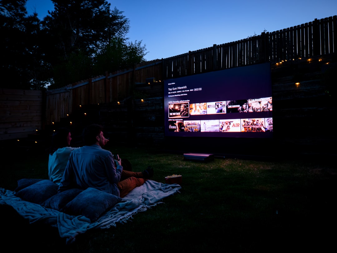 A couple watching an outdoor movie screen in the backyard