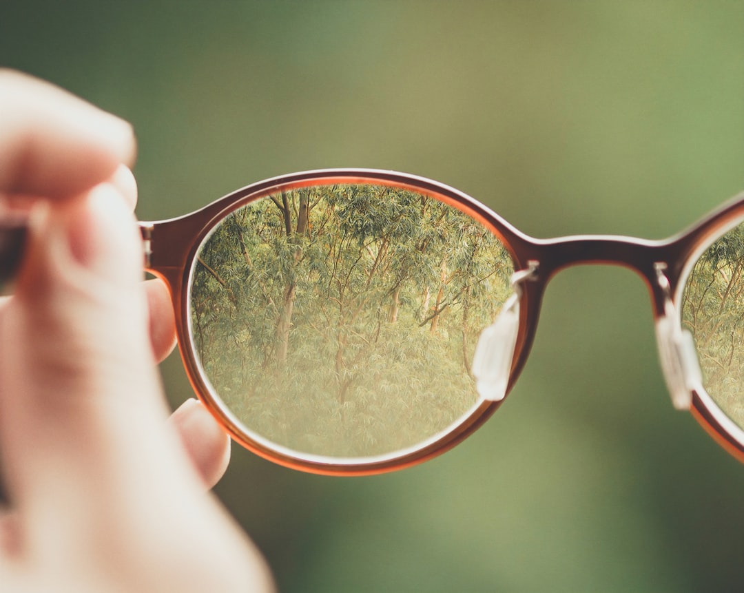 Eyeglasses held up with the reflection visible in the lens