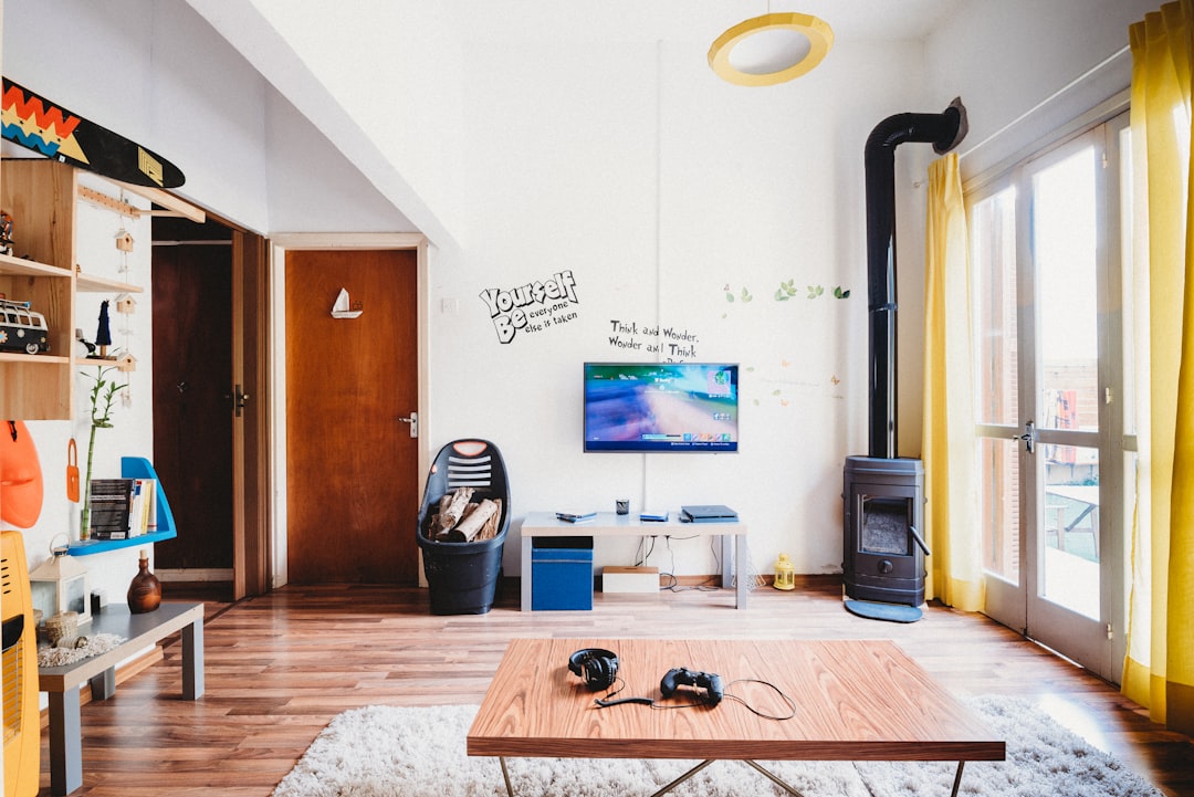 Gaming controller and headphones on a coffee table in front of a wall-mounted TV