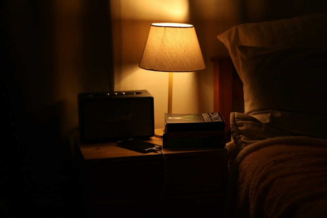 Bedside nightstand with books, phone, and a reading lamp