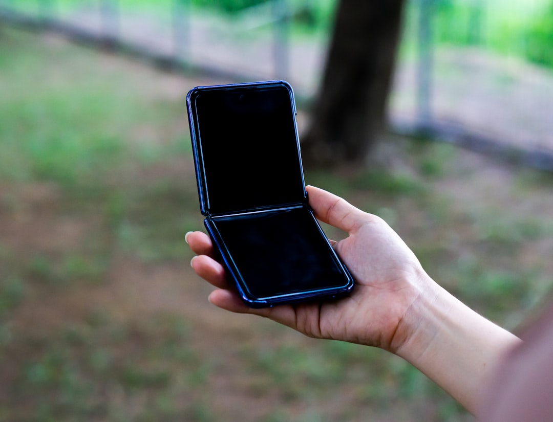 Hand holding an opened foldable phone outdoors