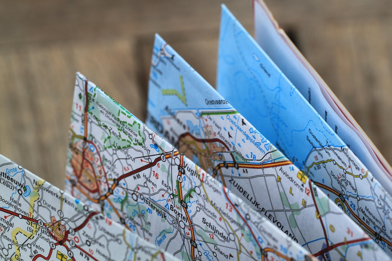 Folded paper road maps standing on a wooden table, the low-tech backup for holiday road trips
