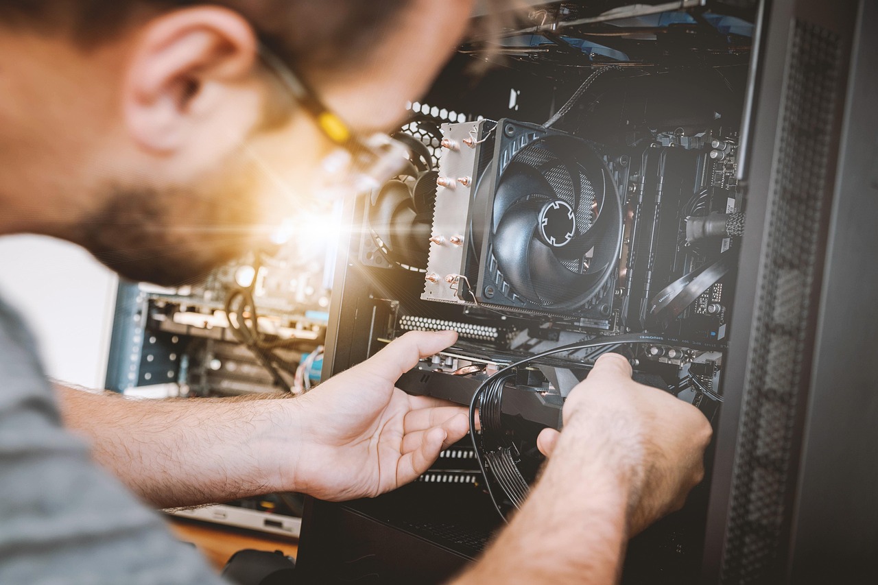 Hands working inside a full-size desktop tower with a large CPU cooler and cables, the bulky setup that compact AI mini PCs now compete with