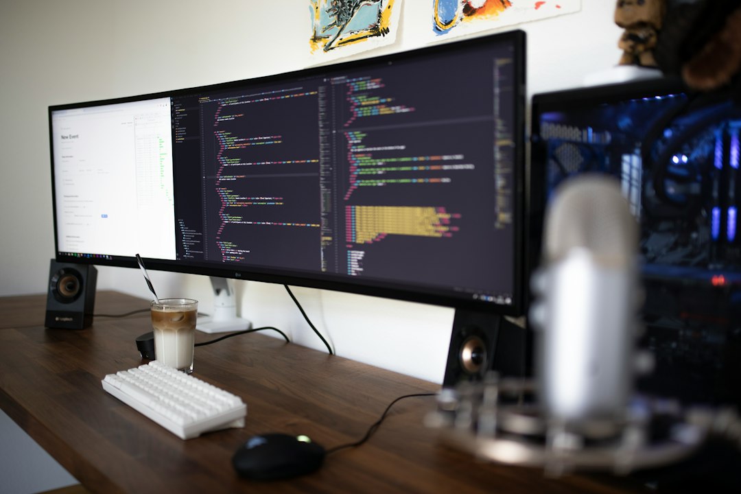 Developer workstation with two monitors showing code, a mechanical keyboard, microphone and speakers