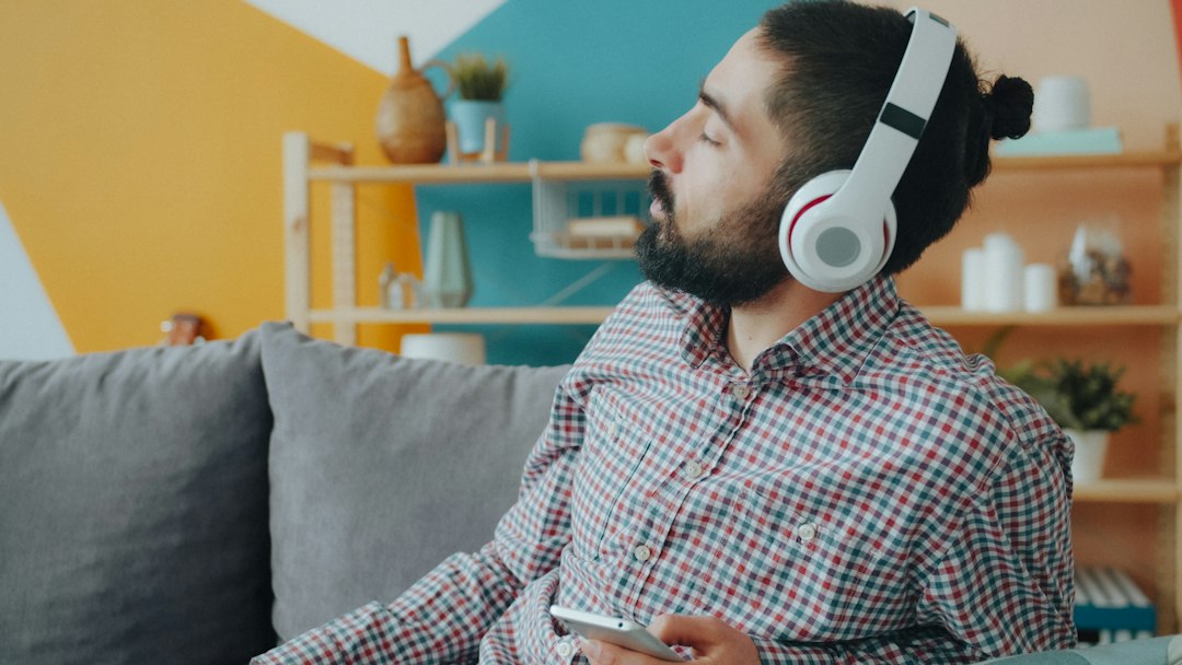A man relaxing on a couch listening to music with over-ear headphones