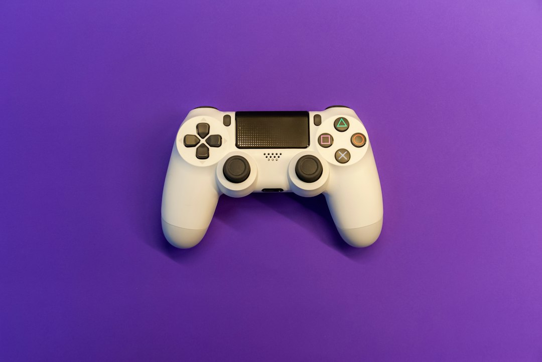 A white game controller lying flat on a bright purple background