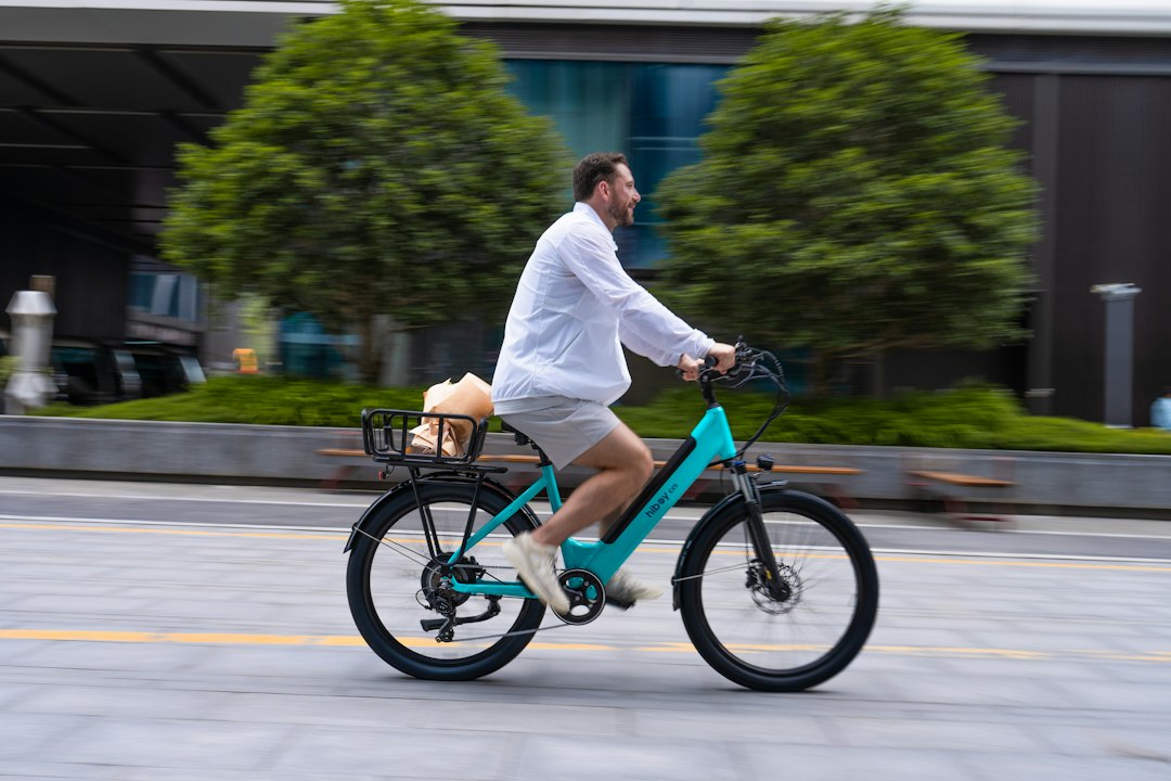 Commuter riding a turquoise electric bike with a loaded rear rack