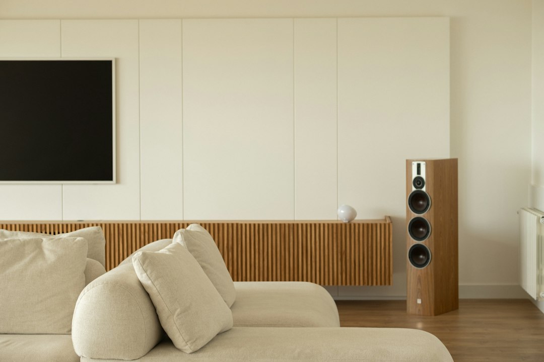 A tall floor-standing speaker in a living room, the wrong scale for a desk
