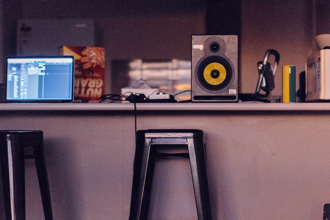 A studio monitor raised on a counter beside a laptop, off the desktop surface
