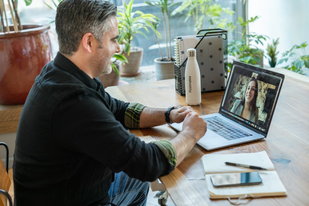 Older man smiling during a laptop video call with a family member on screen