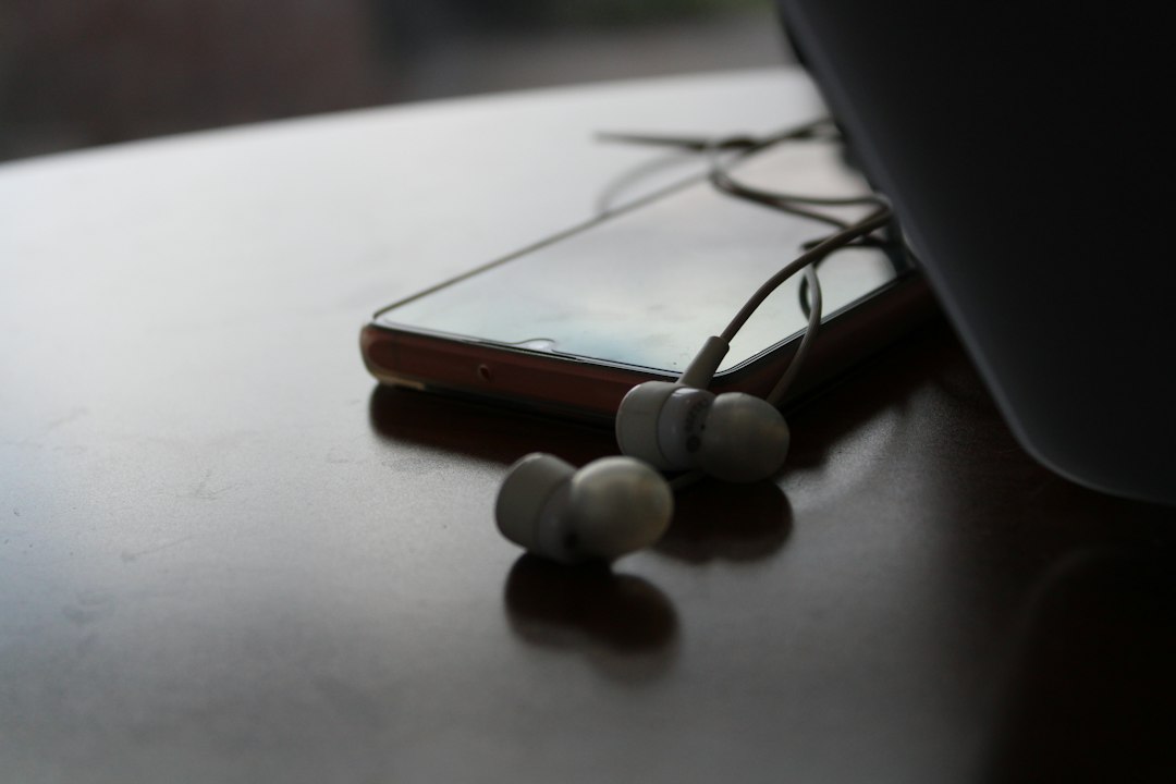 A pair of white wired earbuds resting next to a smartphone, a simple backup gift that never needs a charge