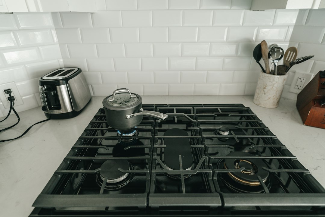 A covered saucepan heating on a gas range in a white kitchen