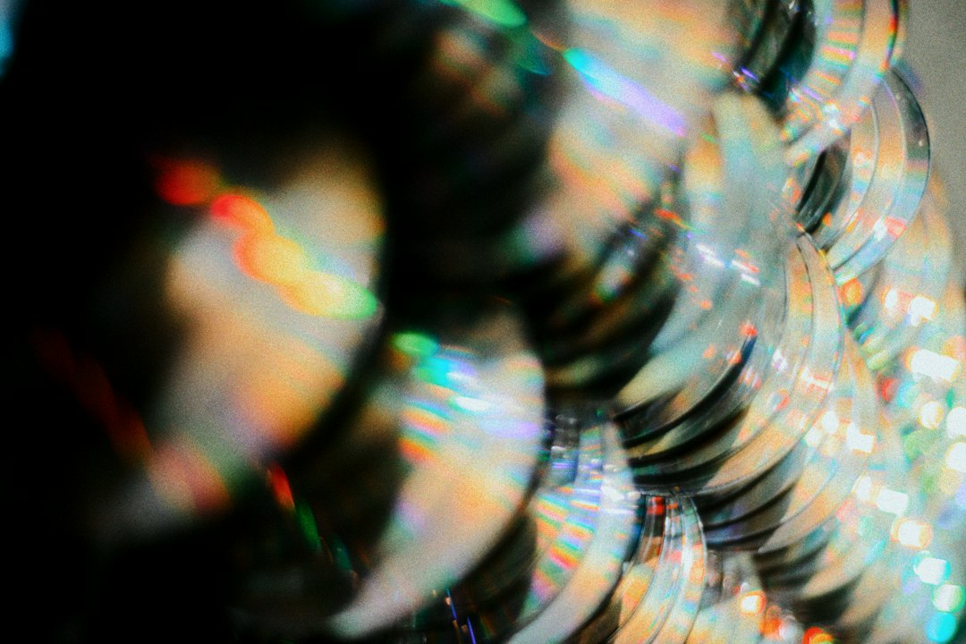 A stack of compact discs catching rainbow reflections