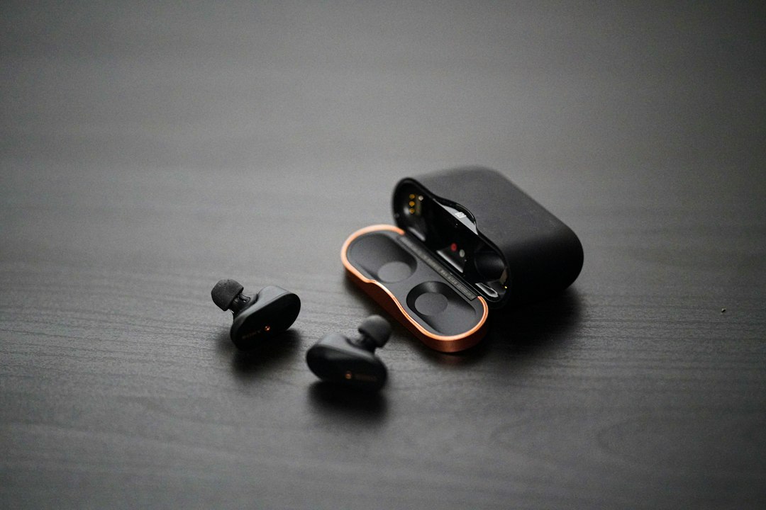 A pair of sealed wireless earbuds beside an open charging case