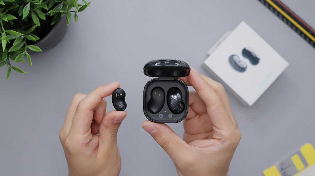 Hand holding wireless earbuds and their open charging case