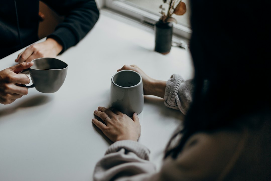 Two people talking over coffee at a cafe table