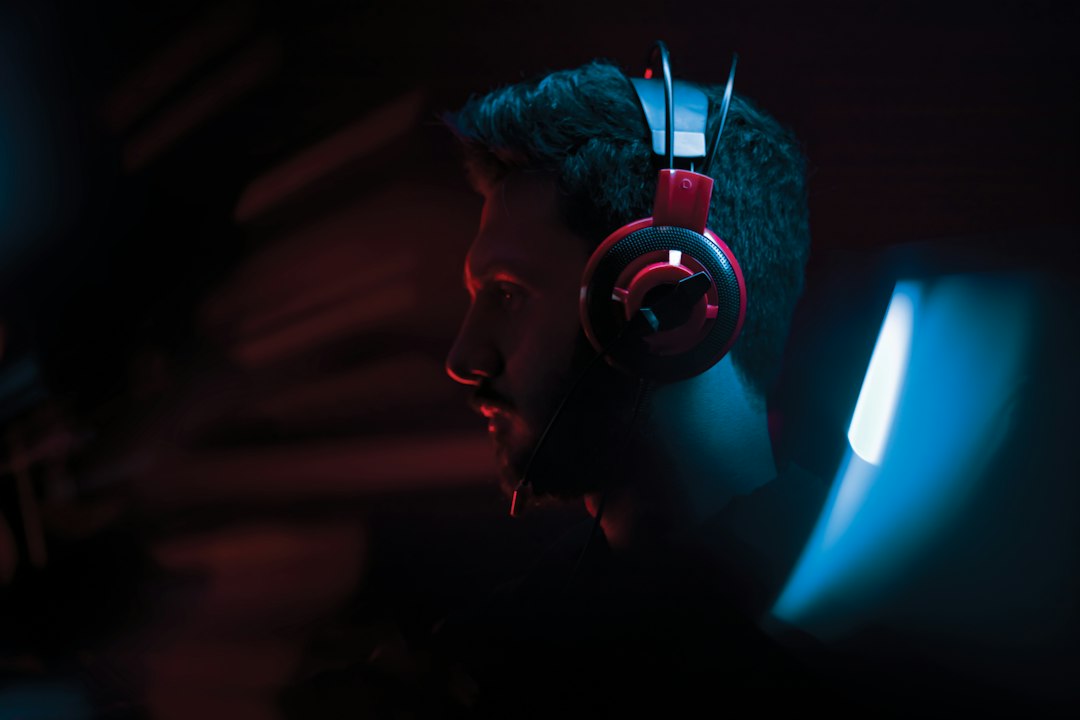 Person wearing wired headphones while gaming on a laptop