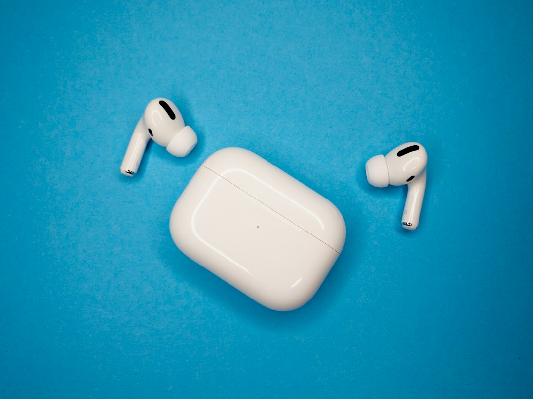 White wireless earbuds and a closed charging case on a blue surface