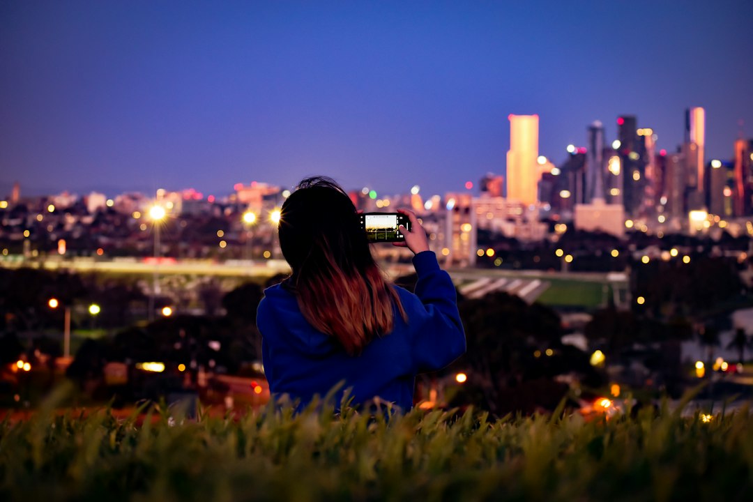 Person raising a phone toward the night sky to capture it
