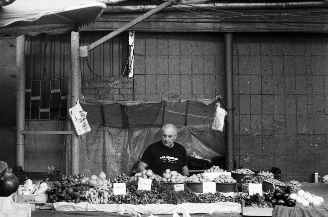 Vendor behind a produce stand at an outdoor market