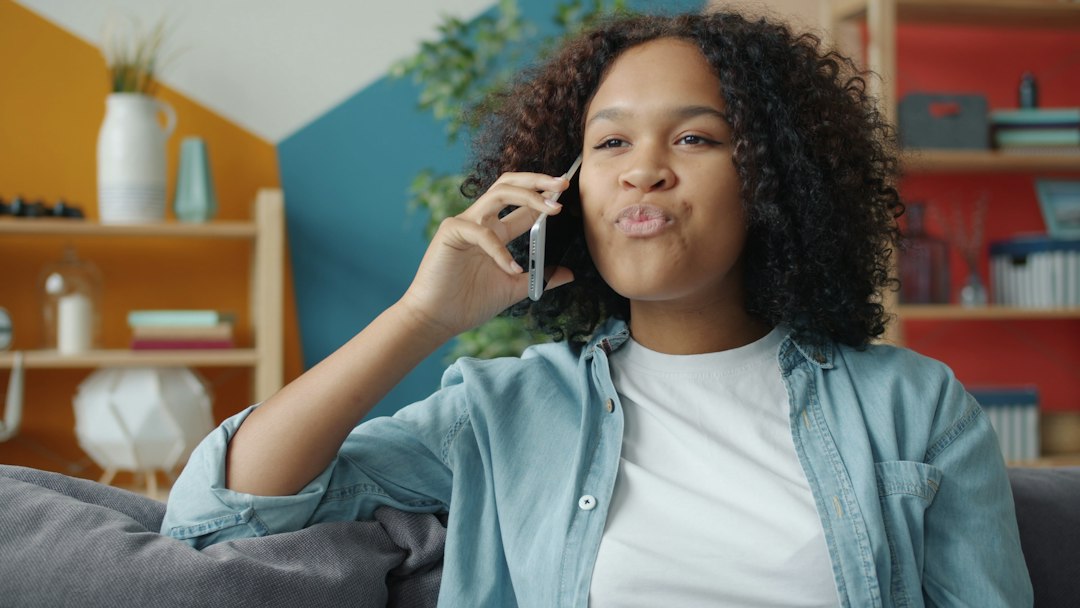 A woman on a living room couch holding a phone to her ear