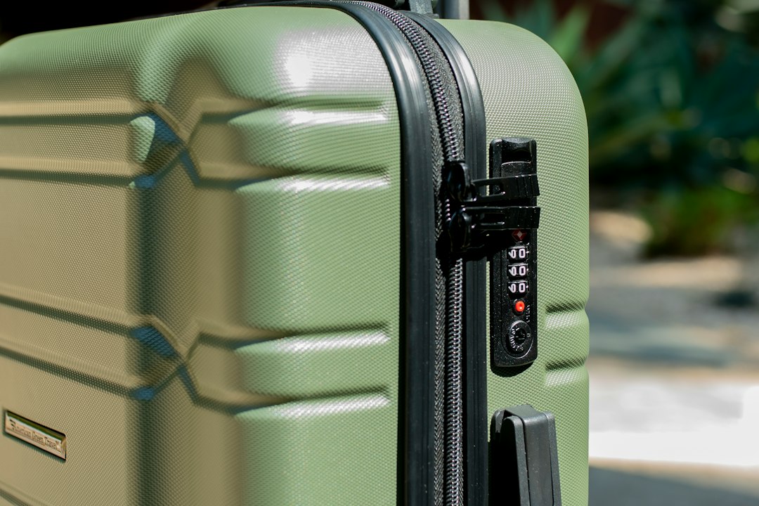 Close-up of a green hard-shell suitcase with a combination lock, the kind of luggage a tracking tag is made for