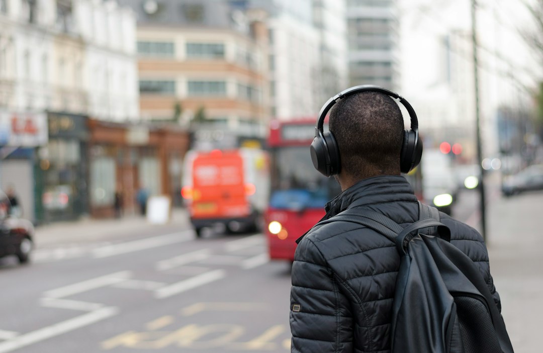 A commuter in over-ear headphones waiting at a city bus stop