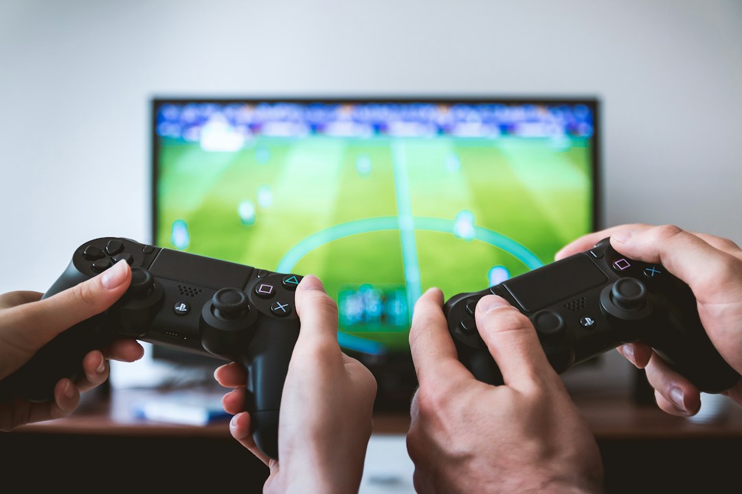 Two people holding game controllers in front of a television showing a soccer game, a shared gaming moment