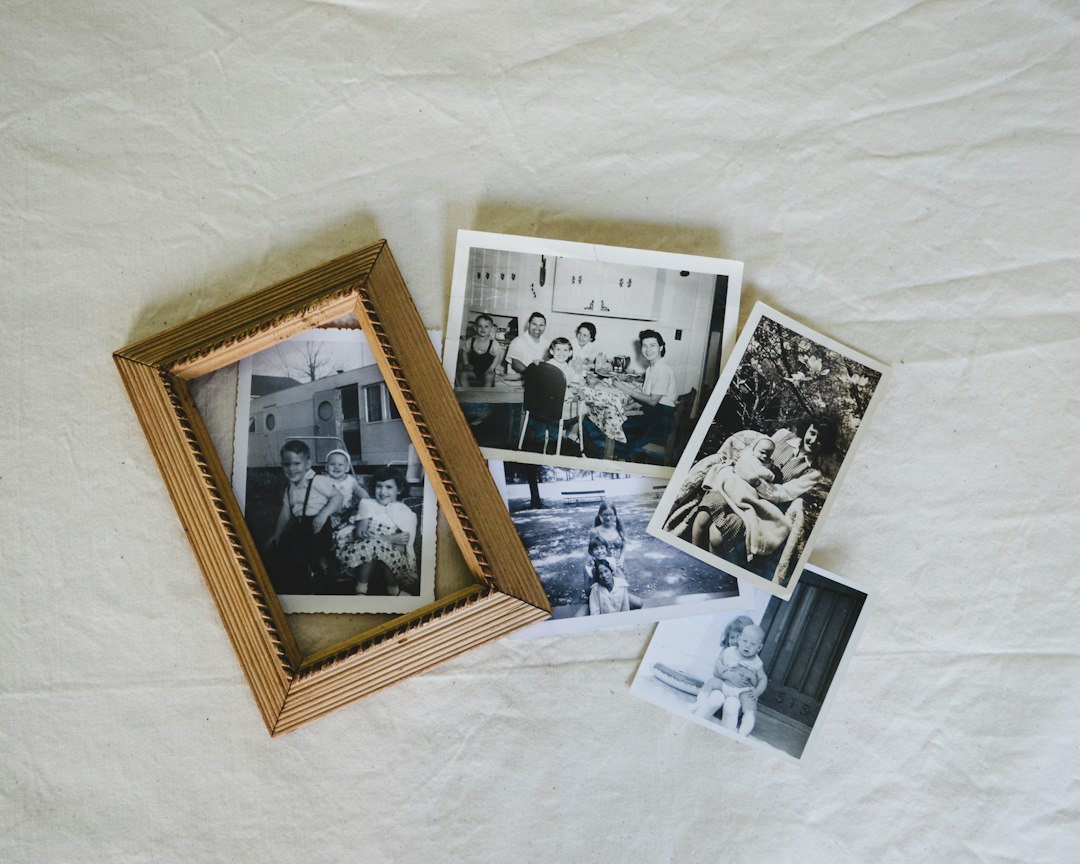 Old family photographs in black and white spread across a table, one framed