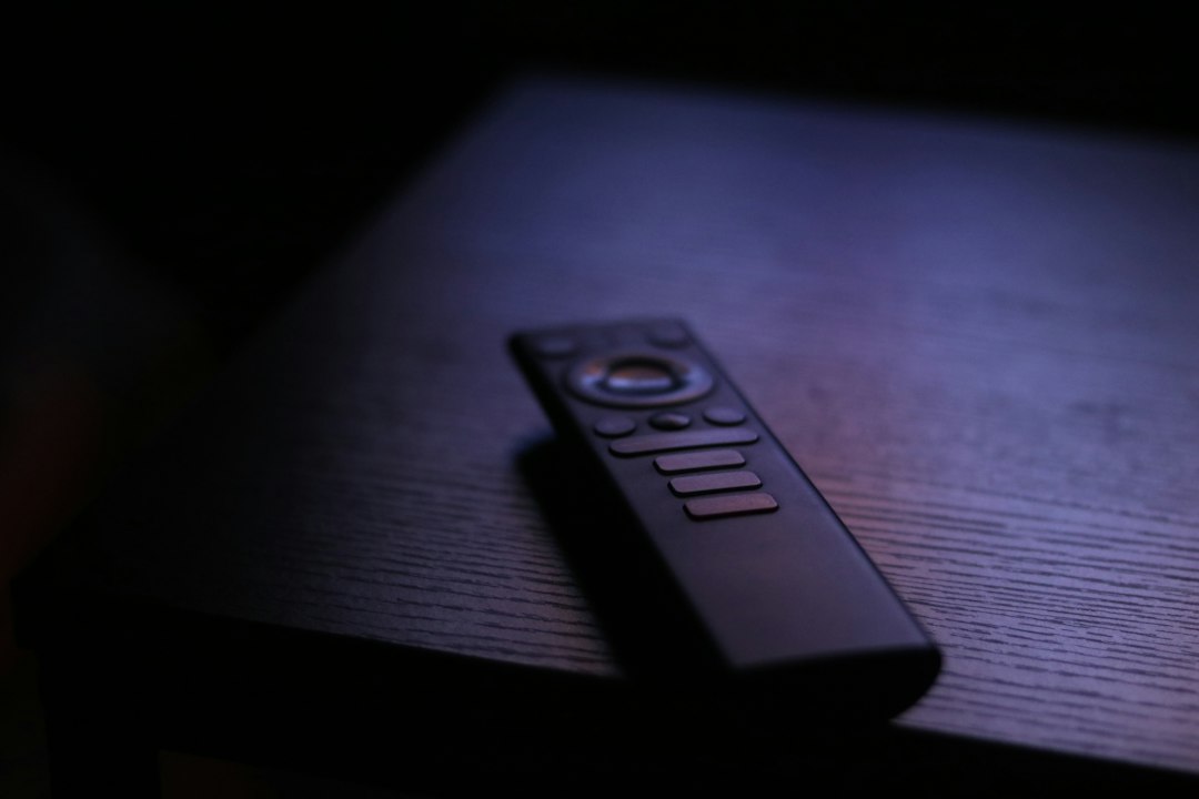 A small remote control on a wooden table, echoing the Kindle Click page-turner