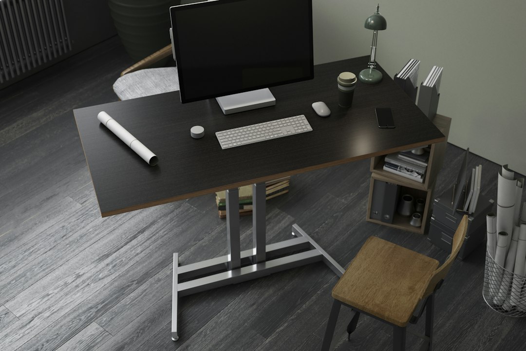 Dark standing desk with a monitor, keyboard, and empty floor space underneath