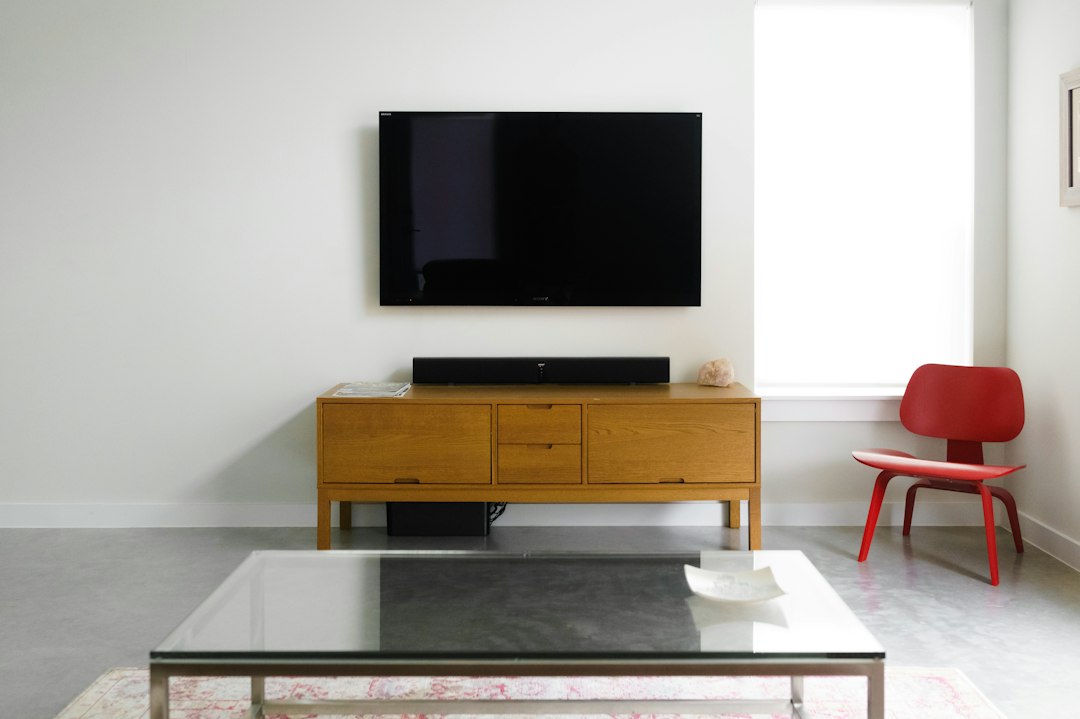 Wall-mounted TV above a wood media console with a compact soundbar beneath it