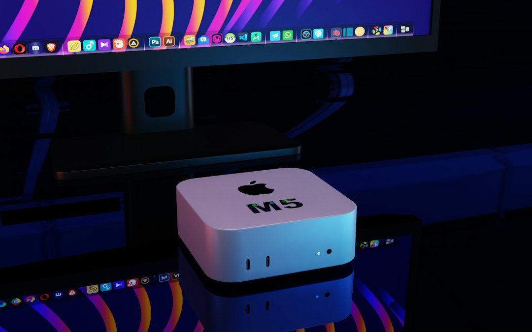 A Mac mini glowing in a dark room beside a monitor