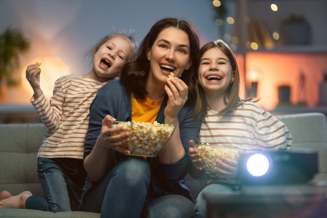 Family laughing together on the couch during movie night